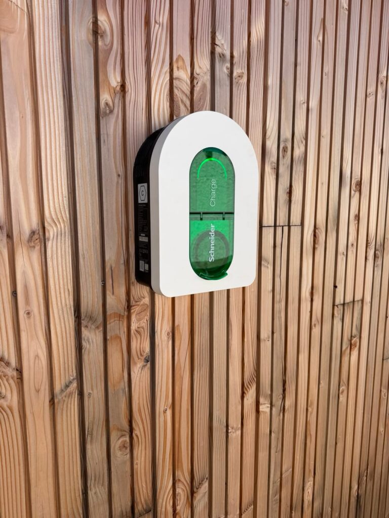 Borne de recharge Schneider montée sur le bardage bois d'un bâtiment collectif — A'dvenir Eco